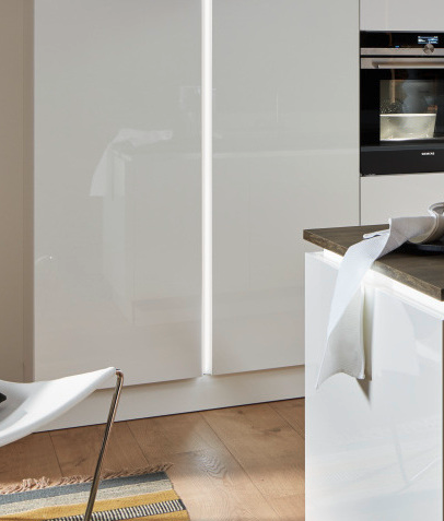 Vertical true handleless profile with integrated LED lighting alongside tall oven housing