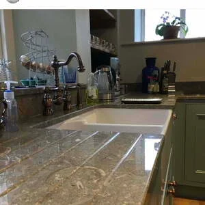 Close up of limestone worktop surface showing the fine-grained texture and subtle natural variation in the stone with visible fossil inclusions in the warm cream background