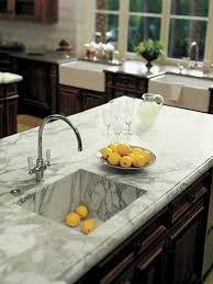 Marble worktop in a kitchen showing the full-length slab view on a peninsular with the natural veining running across the surface and a polished edge profile
