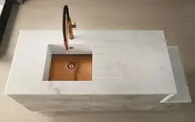 Solid surface worktop showing the seamless continuous material across a kitchen run with integrated upstands and no visible silicone joints where the worktop meets the wall