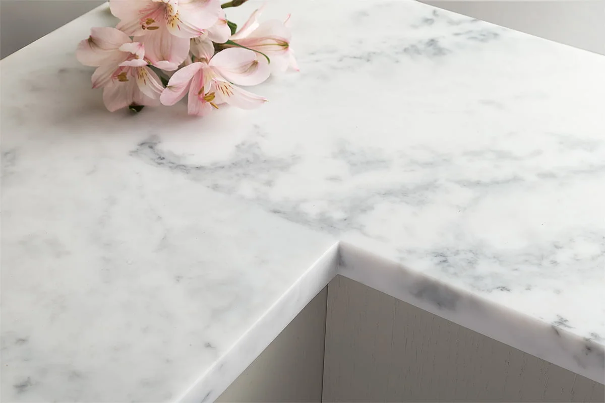 Solid surface worktop in a contemporary kitchen showing the seamless white surface with integrated sink and the continuous material running from the worktop through the bowl with no visible joint at the rim
