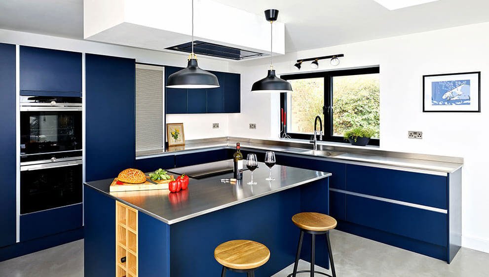 Stainless steel kitchen worktop in a contemporary professional-style kitchen showing the brushed finish, integrated welded sink, and continuous worktop run without visible silicone joints around the bowl