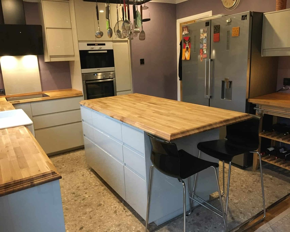 Solid wood worktop showing the full stave construction and natural grain pattern with end grain detail visible on the edge profile in a contemporary kitchen setting