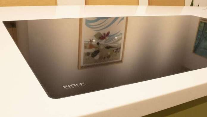 Flush-mounted induction hob showing the glass surface sitting level with the worktop with no visible lip or frame at the edge