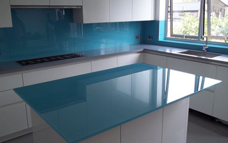 Glass kitchen worktop showing the high-gloss back-painted surface on a contemporary island with the light-reflecting quality of toughened glass and a bold colour finish in a modern handleless kitchen