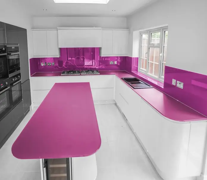 Glass kitchen worktop on an island in a contemporary German kitchen showing the high-gloss surface and light-reflecting properties of toughened back-painted glass in a bold colour