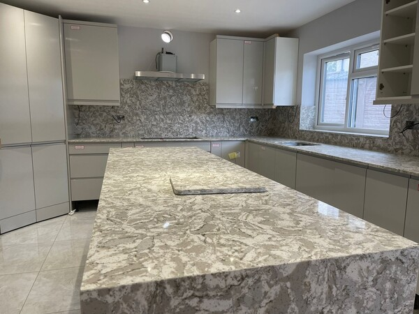 Mid-tone granite worktop showing a grey and white speckled pattern with natural mineral grain and a polished finish
