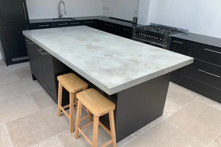 Concrete worktop in a contemporary kitchen showing the distinctive texture and tonal variation of cast concrete with the natural aggregate visible in the polished surface and the architectural presence of the material in a modern kitchen setting
