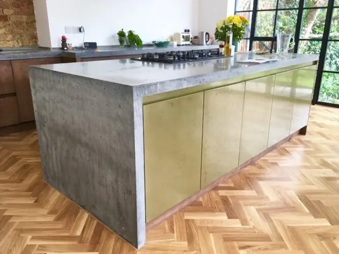 Concrete worktop on a kitchen island showing the architectural presence and visual weight of cast concrete with integrated features and the distinctive character of the material in a design-led contemporary kitchen project