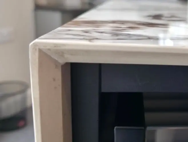 Porcelain worktop mitre edge showing the 45-degree join on the front face of a built-up edge with pattern continuity on full-body porcelain