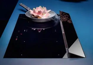 Falmec vented hob showing the rear extraction flap in the open position during cooking with the full worktop surface visible around the hob