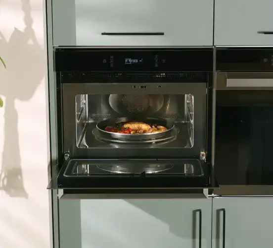 Microwave with turntable showing the rotating glass plate on the cavity floor that rotates food through the microwave energy field for even heating with the typical circular restriction on container placement that turntable design creates