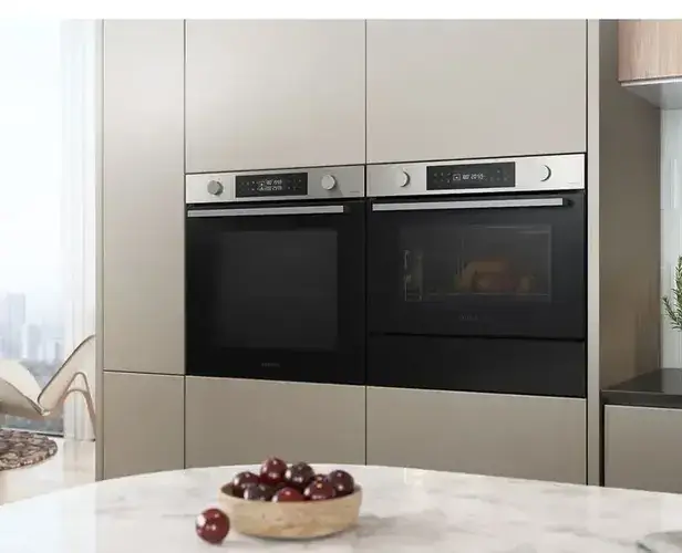Single oven and combination microwave side by side in a tall housing unit showing how the two different appliance heights a full-size 595mm single oven and a 450mm compact combi microwave fit together in an appliance tower configuration in a contemporary UK kitchen