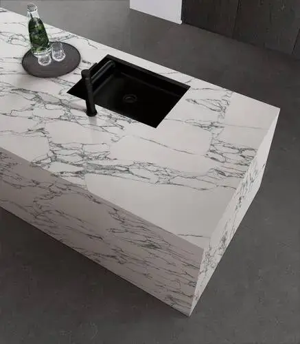 Kitchen island wrapped in quartz showing the worktop surface continuing down the visible side faces of the island creating a monolithic appearance with the quartz material running continuously from the top surface to near floor level on the island sides