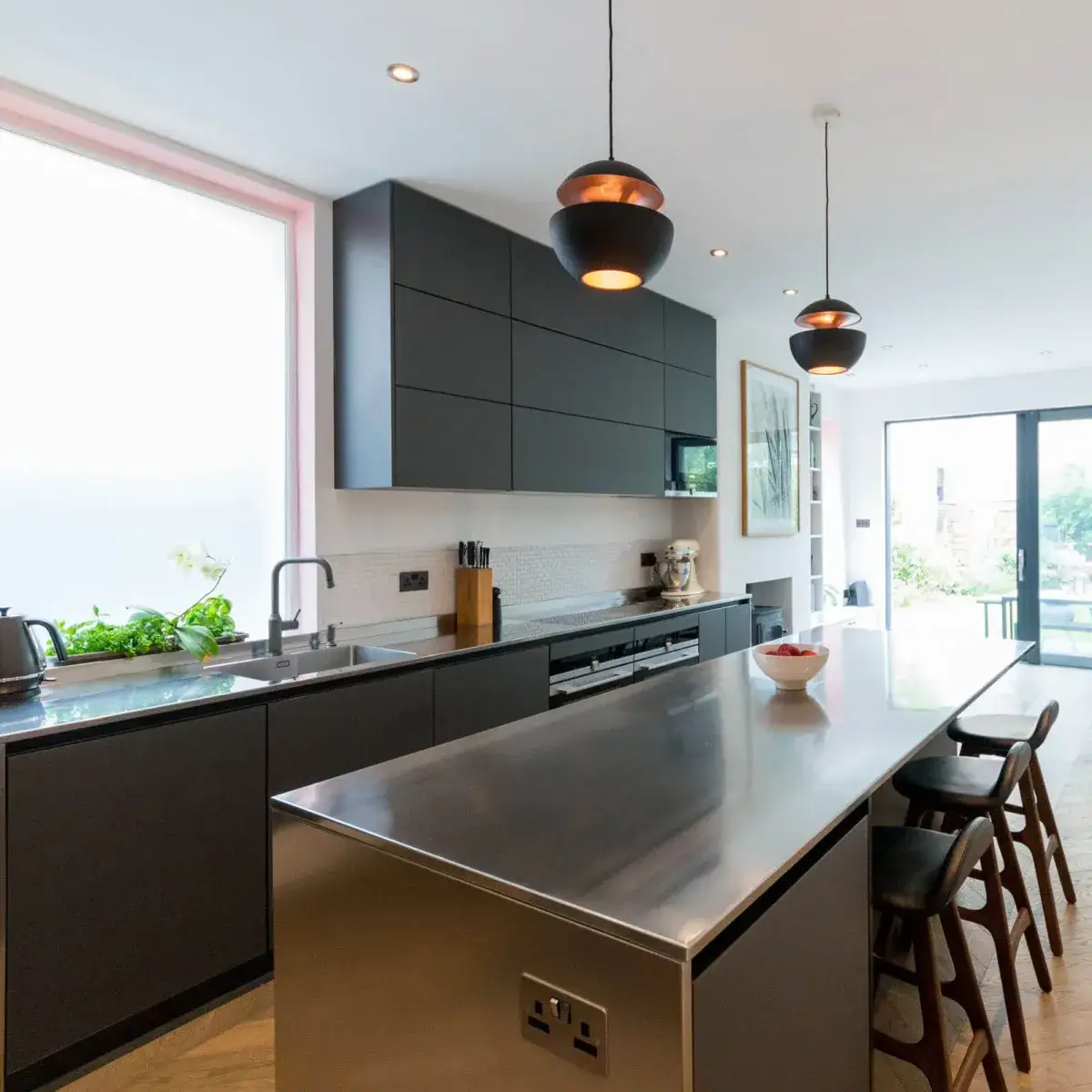 Stainless steel kitchen worktop showing the brushed finish surface and integrated sink in a contemporary kitchen with handleless cabinetry and the professional aesthetic of commercial-grade steel in a domestic setting